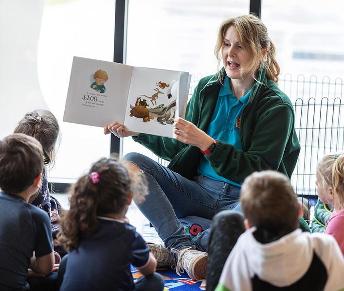 A lady reading a book to children
