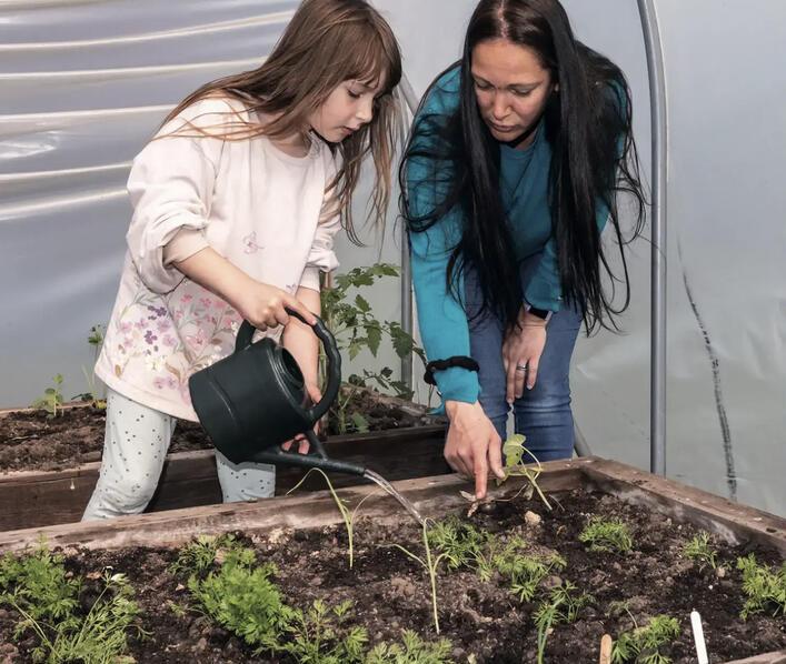 A lady and a girl tend to plants 